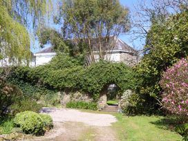 A garden with an archway and flowering bushes at The Music Room near Aveton Gifford