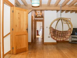 A hallway with a hanging chair and wooden door at The Roundhouse in Halwell