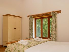 A bedroom with a bed, wardrobe, and window at The Hay Barn in Halwell