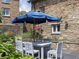 An outdoor dining area with a table and umbrella at The Hay Barn in Halwell