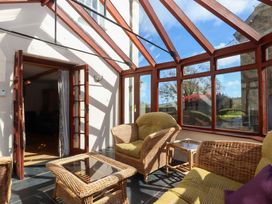 A conservatory with wicker furniture and a glass table at Oak Tree in Halwell