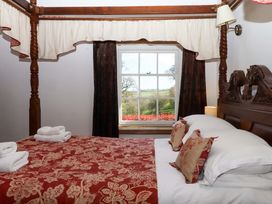 A bedroom with a four-poster bed and a window at Oak Tree in Halwell