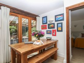 A dining room with a wooden table and flower vase at Fixit Cottage in Kingsbridge