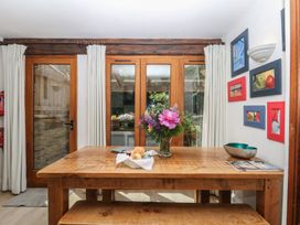 A dining room with a wooden table and flowers at Fixit Cottage in Kingsbridge