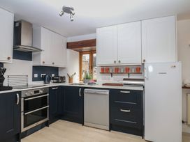 A kitchen with cabinets, sink, oven, and refrigerator at Fixit Cottage in Kingsbridge