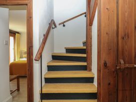 A staircase with handrail leading to an upper floor at Fixit Cottage in Kingsbridge