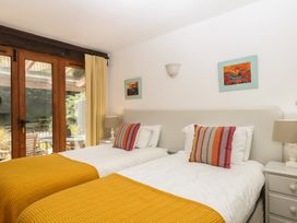 A bedroom with twin beds and sliding doors to a patio at Fixit Cottage in Kingsbridge