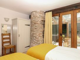 A bedroom with a stone wall and two beds at Fixit Cottage in Kingsbridge