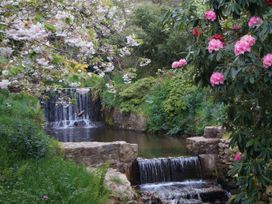 A stream with waterfalls and flowering trees at The Clock House in Ivybridge