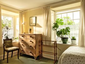 A bedroom with a dresser, chair, and plants at Parnacott in Holsworthy