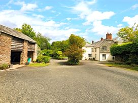 An outdoor view of a house and barn with trees at Parnacott in Holsworthy