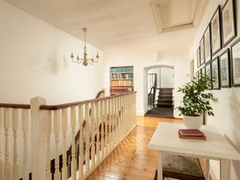 A hallway with a staircase and a bookcase at Parnacott in Holsworthy