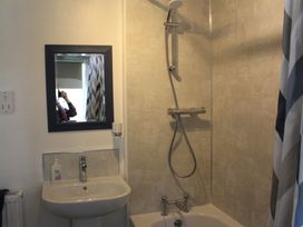 A bathroom with a sink soap dispenser mirror shower head and a bathtub with shower curtain at Tom in Blisland