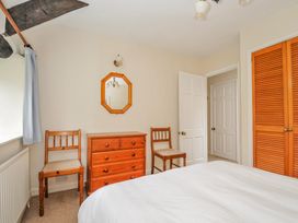 A bedroom with a bed, chairs, and a chest of drawers at Tumrose Cottage in Blisland