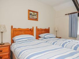 A bedroom with two beds, bedside table, and lamp at Tumrose Cottage in Blisland