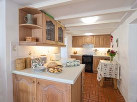 A kitchen with wooden cabinets and a table setting at Agar Cottage in Trelights, near Port Isaac
