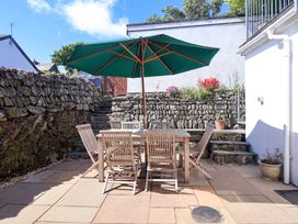 A garden with a table and chairs under an umbrella at Agar Cottage, Trelights, near Port Isaac