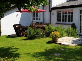 A garden with a table and chairs under a parasol at Orchard Lodge in Boscastle