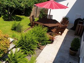 A garden with a wooden table and chairs under an umbrella at Orchard Lodge Boscastle