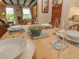 A dining table set with plates and glasses at Primrose Cottage, Edmonton, near Wadebridge