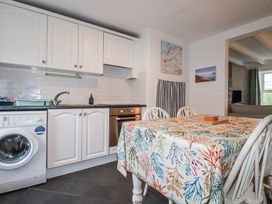 A kitchen with appliances and a dining table at Kingfisher Cottage in Edmonton, near Wadebridge