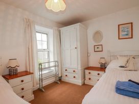 A bedroom with two beds and a wardrobe at Kingfisher Cottage in Edmonton, near Wadebridge