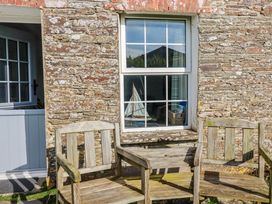 An outdoor area with wooden chairs and a window at Kingfisher Cottage, Edmonton, near Wadebridge