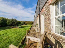 A garden with a wooden bench and grass at Kingfisher Cottage in Edmonton, near Wadebridge