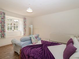 A bedroom with a bed, sofa, curtains and a mirror at Tregonhawke Farmhouse in Millbrook