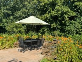 An outdoor seating area with a table and chairs under an umbrella at Kingbarth in Lerryn