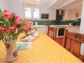 A kitchen with a table and flowers at Mural Cottage in Mousehole