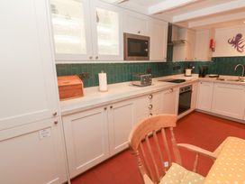 A kitchen with appliances and cabinets at Mural Cottage in Mousehole