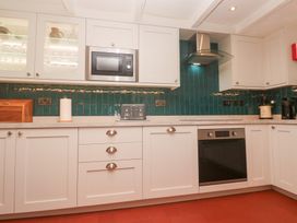 A kitchen with cabinets and appliances at Mural Cottage in Mousehole