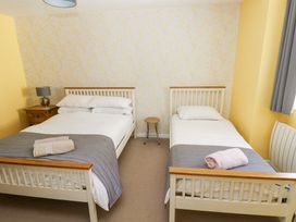 A bedroom with two beds bedside tables a lamp and folded towels at 4 Hanbury Lodge in Pentlepoir