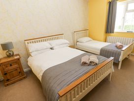 A bedroom with two beds a wooden nightstand a lamp and a window at 4 Hanbury Lodge Pentlepoir