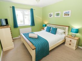 A bedroom with a bed chest of drawers bedside tables and a window at 4 Hanbury Lodge in Pentlepoir
