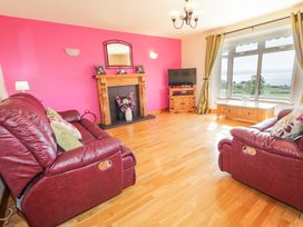 A living room with two red leather sofas wooden fireplace and a large window with curtains at Tullyally in Redcastle