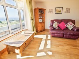 A living room with a large window a wooden coffee table a wooden cabinet and a red leather sofa with cushions at Tullyally in Redcastle