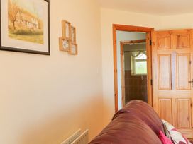 A room with a brown leather sofa wooden door and framed paintings on the wall at Tullyally in Redcastle