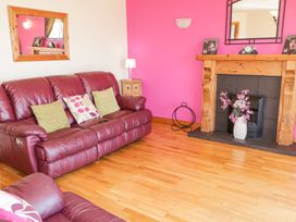 A living room with two leather sofas a wooden fireplace and a pink accent wall at Tullyally in Redcastle