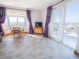 A room with a wooden dining table and chairs a television on a wooden cabinet and glass sliding doors leading to a patio at Tullyally in Redcastle