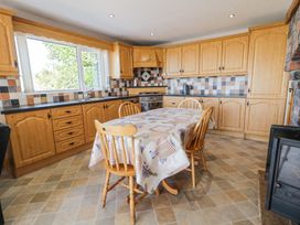 A kitchen with wooden cabinets a dining table with chairs and a window at Tullyally in Redcastle