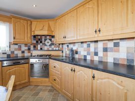 A kitchen with wooden cabinets tiled backsplash gas stove oven dishwasher and kettle on counter at Tullyally in Redcastle