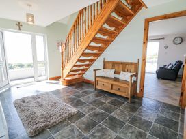 A hallway with tiled floor wooden staircase and wooden bench with cushions at Tullyally in Redcastle