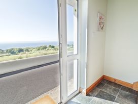 An open glass door leading outside with a view of greenery and the sea at Tullyally in Redcastle