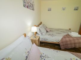 A bedroom with two beds with floral bedding a wooden nightstand with a lamp and folded towels on one bed at Tullyally in Redcastle