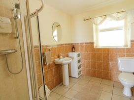 A bathroom with a shower enclosure sink toilet small storage unit and window at Tullyally in Redcastle