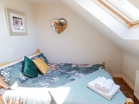 A bedroom with a floral bedspread teal and yellow pillows a heart shaped mirror and a skylight window at Tullyally in Redcastle