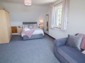 A bedroom with a double bed sofa armchair wardrobe and a window at Tullyally in Redcastle