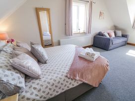 A bedroom with a double bed with folded towels a full length mirror a window with curtains and a sofa at Tullyally in Redcastle